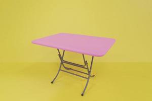 table pliante rose les pieds de la table sont des cadres en acier dans la chambre jaune. Objet de maquette 3d. illustration 3drender. photo
