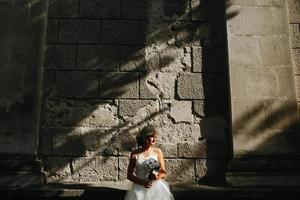 mariée posant sur fond de mur de pierre photo