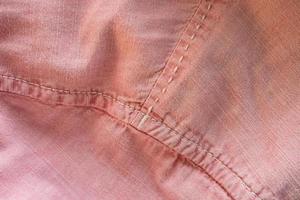 fond de tissu texturé de couleur rose avec des points de suture. place pour le texte. plat. fermer. photo