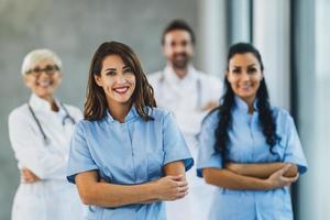 équipe médicale d'infirmières et de médecins debout avec les bras croisés et regarde la caméra photo