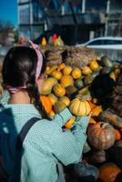 femme avec une petite citrouille parmi la récolte d'automne photo