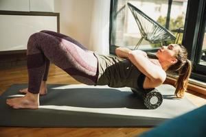 femme faisant de l'exercice avec un rouleau en mousse à la maison photo