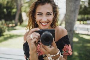 portrait d'une femme avec un appareil photo numérique souriant et regardant la caméra