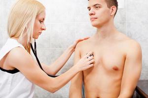 examinant un jeune homme avec un stéthoscope photo