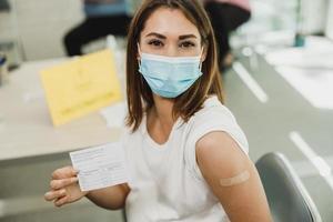 femme enceinte tenant une carte de vaccination covid-19 photo