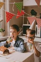 les garçons fêtent leur anniversaire. attirail de l'anniversaire des enfants. frères couverts de gâteau sur leurs visages. fête de famille à la maison photo