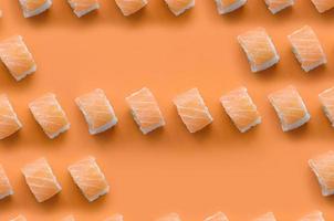 rouleaux de philadelphie au saumon sur fond orange. vue de dessus du minimalisme motif plat avec de la nourriture japonaise photo