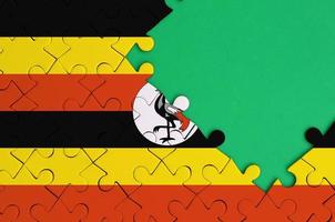 le drapeau de l'ouganda est représenté sur un puzzle terminé avec un espace de copie vert gratuit sur le côté droit photo