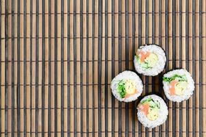 les rouleaux de sushi reposent sur un tapis de couture en paille de bambou. cuisine asiatique traditionnelle. vue de dessus. minimalisme à plat tourné avec espace de copie photo