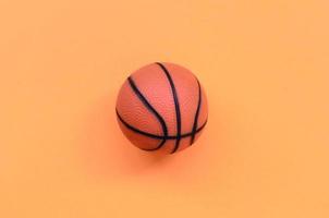 petite balle orange pour le jeu de sport de basket-ball se trouve sur fond de texture de papier de couleur orange pastel mode dans un concept minimal photo