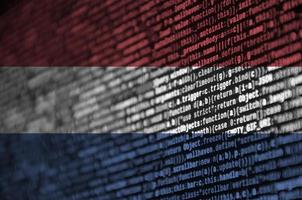 drapeau néerlandais est représenté sur l'écran avec le code du programme. le concept de technologie moderne et de développement de site photo