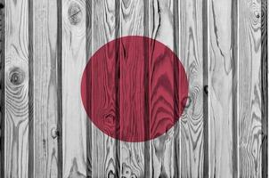 drapeau du japon représenté dans des couleurs de peinture vives sur un vieux mur en bois. bannière texturée sur fond rugueux photo