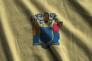 drapeau de l'état américain du new jersey avec de gros plis agitant de près sous la lumière du studio à l'intérieur. les symboles et couleurs officiels de la bannière photo