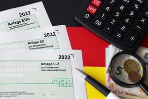 allemand différents formulaires vierges de déclaration fiscale - anlage eur, anlage sz et anlage luf. les documents se trouvent avec une calculatrice, un stylo et de l'argent européen photo