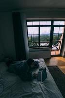 jeune femme travaillant sur un ordinateur portable en position couchée sur le lit photo