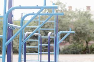 bars sportifs en bleu sur le fond d'un terrain de sport de rue pour l'entraînement en athlétisme. équipement de gym athlétique en plein air. photo macro avec mise au point sélective et arrière-plan extrêmement flou