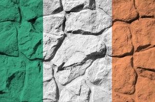 drapeau irlandais représenté dans des couleurs de peinture sur un vieux mur de pierre agrandi. bannière texturée sur fond de paroi rocheuse photo