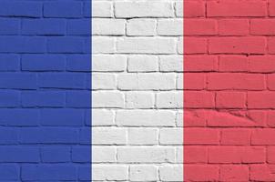 drapeau de la france représenté dans des couleurs de peinture sur un vieux mur de briques. bannière texturée sur fond de maçonnerie de gros mur de briques photo