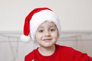 portrait d'un garçon mignon dans un chapeau de père noël. drôle d'enfant souriant. cadeaux, jouets, joie, célébration. photo