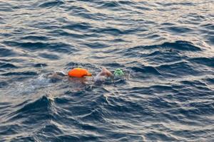 nageur nageant en eau libre dans la mer méditerranée avec une bouée de sécurité photo