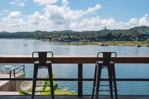 bar en bois avec chaises sur terrasse au bord du lac en journée ensoleillée