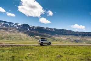 grande voiture garée sur un chemin de terre entre la montagne et le pré par une journée ensoleillée en été photo