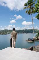 jeune homme asiatique se tenait à contempler sur le patio et le village traditionnel au bord du lac en journée ensoleillée
