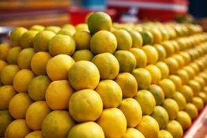 une pile de lignes jaunes mûres et sucrées sur tout l'écran sur le marché. fond citron vert et citrons. citrons et citron vert bio frais chez un agriculteur local
