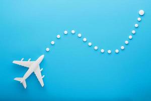 modèle blanc d'un avion de passagers avec des points de trajectoire en pointillés isolés sur fond. la route de l'avion dans les pays et le ciel. photo