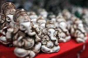 la statuette en pierre de ganesh est verte, contrastant avec le groupe de ganesh léger sur le comptoir du marché indien photo