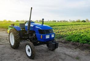 le tracteur agricole bleu se dresse sur le terrain. application de machines agricoles à la récolte. modernisation et automatisation des processus de la ferme. subventions et remboursements d'impôts pour l'achat de nouveaux équipements de travail photo