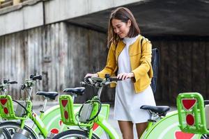 vélo de ville - femme asiatique utilisant le système de partage de vélos publics de la ville. faire du vélo des vélos de ville de stationnement professionnels féminins après avoir fait du vélo sur un vélo de ville. photo