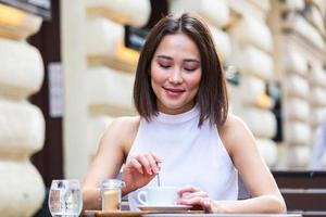 belle jeune femme asiatique avec une tasse de café. femme aime le café frais le matin avec le lever du soleil au café belle femme buvant du café le matin assis près de la fenêtre photo