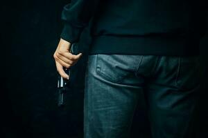 un homme vêtu de vêtements sombres tient un pistolet. photo