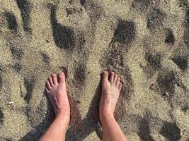 jambes, pieds sur fond de sable doré jaune friable en vacances sur la plage dans un paradis tropical chaud de l'est photo