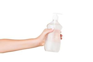 main féminine tenant une bouteille de crème de lotion isolée. fille donne des produits cosmétiques sur fond blanc photo