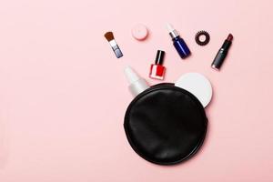 vue de dessus d'un ensemble de produits de maquillage et de soins de la peau qui débordent du sac de cosmétiques sur fond rose. notion de beauté photo