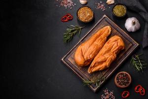 savoureux filet de poitrine de poulet fumé aux épices et herbes sur une planche à découper en bois photo