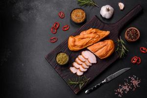 savoureux filet de poitrine de poulet fumé aux épices et herbes sur une planche à découper en bois photo