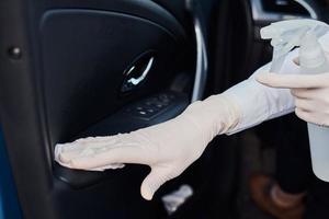 femme nettoyant une voiture avec un spray désinfectant pour se protéger du coronavirus photo