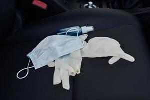 masque de protection gants médicaux et désinfectant antibactérien sur le siège auto photo