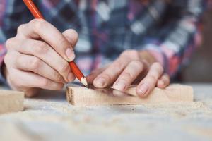 mains de charpentier prenant la mesure avec un crayon de planche de bois. photo