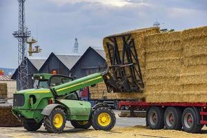 varna,bulgarie,septembre,19,2016,chariot élévateur télescopique johndeere déchargeant les balles du camion. vue de jour photo