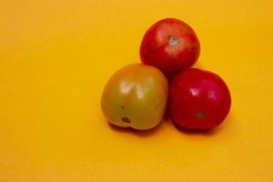 trois tomates isolées sur jaune photo