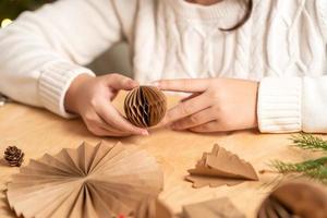 fille fait des décorations d'arbre de noël en papier avec ses propres mains. instruction étape par étape photo
