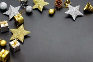 étoiles de couleur or-argent, boîte-cadeau et boules décoratives sur fond noir avec espace de copie. photo