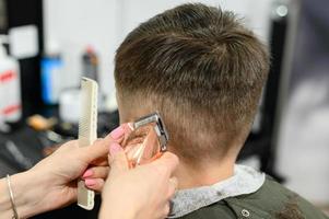 un adolescent dans un salon de beauté se fait couper les cheveux, un coiffeur coupe les cheveux d'un adolescent. photo