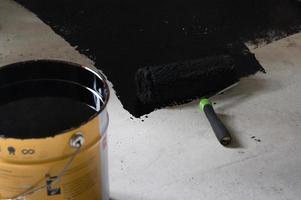 application de résine chaude sur le sol pour l'imperméabilisation, rouleau et seau de résine. photo