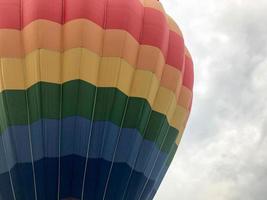 Grand ballon volant multicolore à rayures rondes et lumineuses de couleur arc-en-ciel avec un panier contre le ciel le soir photo