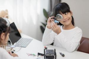 deux étudiants asiatiques apprennent le codage des voitures robotiques et des câbles de carte électronique dans la tige, la vapeur, le code informatique de la technologie des sciences de l'ingénierie mathématique dans la robotique pour les concepts pour enfants. photo